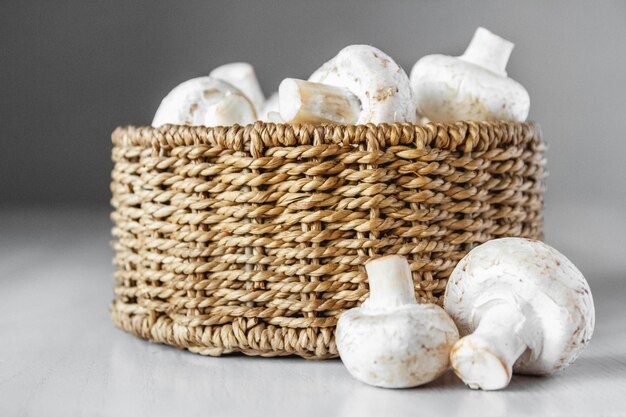 Champignons Champignons in einem runden Weidenkorb auf einem weißen Holztisch