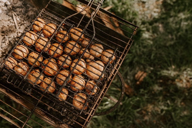 Champignons de cogumelos redondos pequenos e idênticos brancos empilhados em fileiras iguais em um churrasco na grelha.