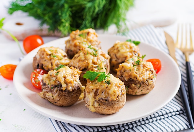 Champiñones al horno rellenos de carne picada de pollo, queso y hierbas en un plato ligero