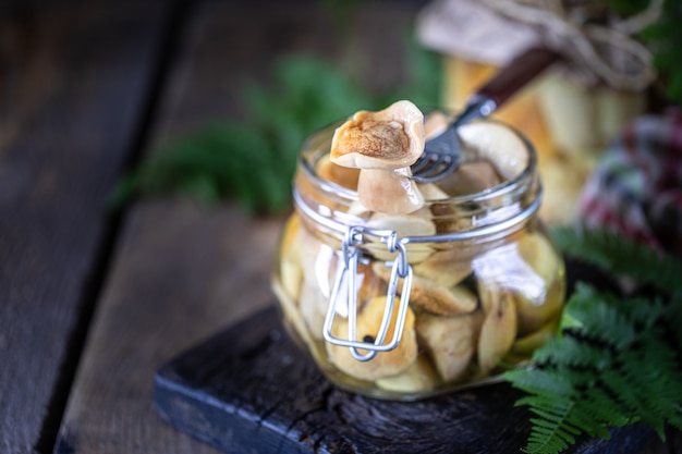 Champiñones comestibles enlatados en un frasco de vidrio. Champiñones en escabeche caseros