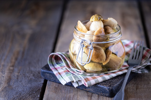 Champiñones comestibles enlatados en un frasco de vidrio. Champiñones en escabeche caseros