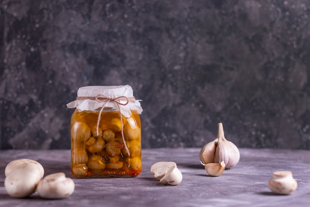 Champiñones fermentados enlatados en un frasco de vidrio con ajo y laurel