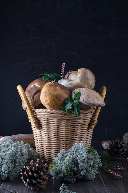 Foto champiñones frescos en la cesta, boletus cosechado en el bosque en la superficie de madera oscura