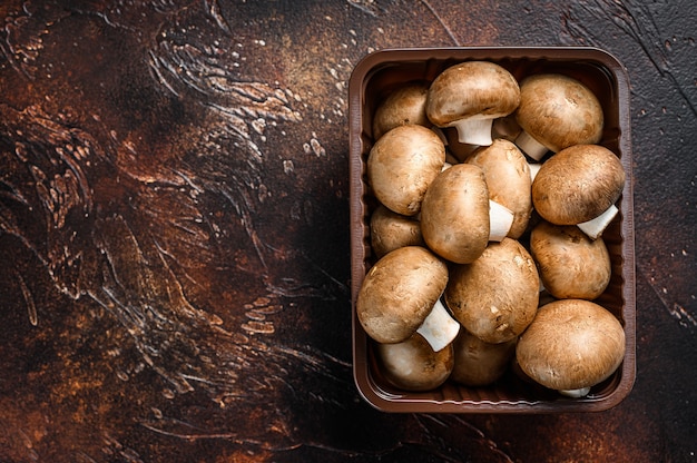 Champiñones frescos crudos en una caja de plástico