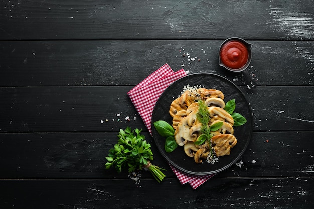 Champiñones fritos con sésamo y albahaca en un plato negro sobre fondo negro Vista superior Espacio libre para el texto