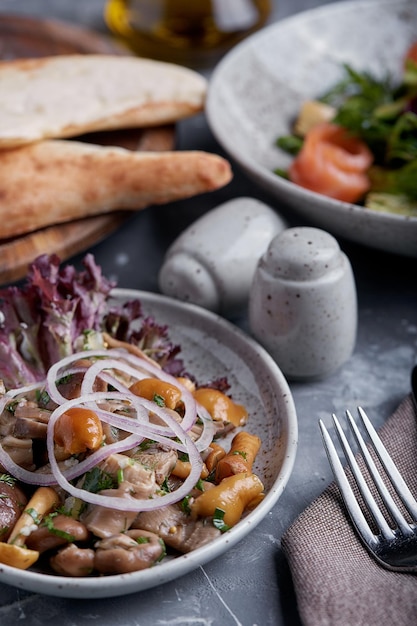 Champiñones marinados y cebollas en un plato sobre un fondo gris