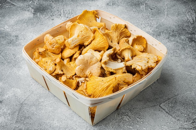 Champiñones rebozuelos del bosque colocados en un contenedor de caja de madera sobre fondo de mesa de piedra gris