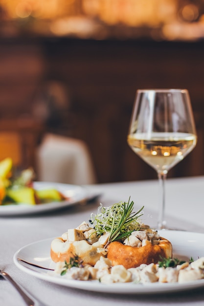 Champiñones rellenos en el plato blanco con una copa de vino