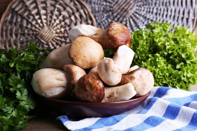 Champiñones silvestres en un plato con hierbas y verduras en la mesa