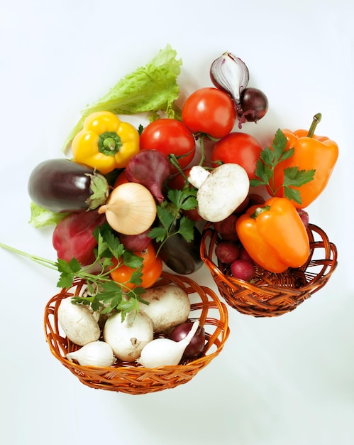 Champiñones y una variedad de verduras frescas en una cesta de mimbre aislada en un blanco