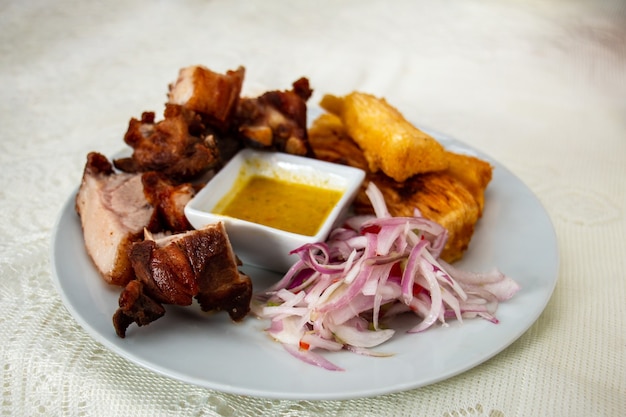 Chancho al Palo oder holzgebratenes Schweinefleisch mit Yuccas-Zwiebelsalat und gemahlenem Chili peruanisches Essen