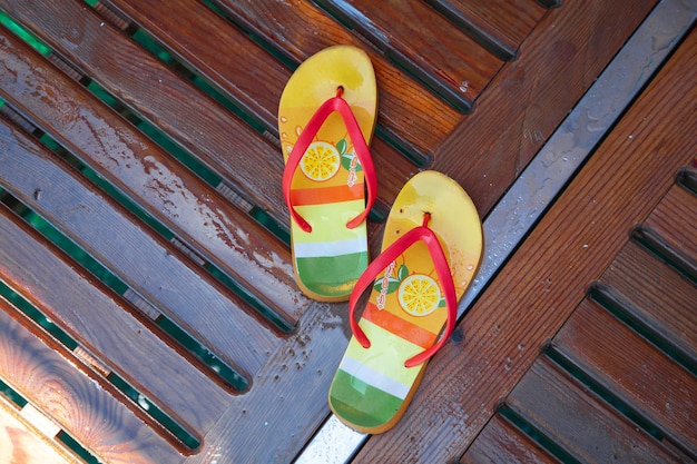 chanclas, colores de verano naranja y amarillo en el muelle. zapatillas en tablero de madera.