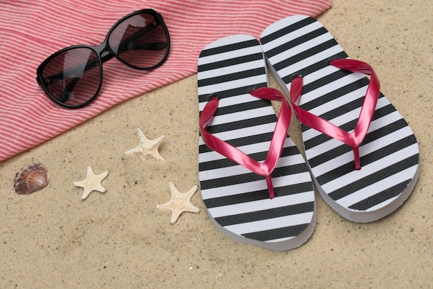 Chanclas y gafas de sol en la arena Concepto de vacaciones de verano