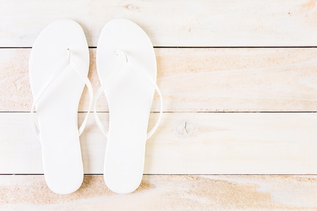 Foto chanclas de mujer brillantes sobre una tabla de madera.