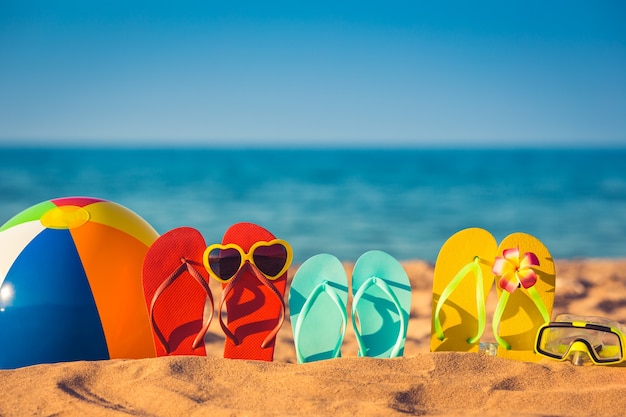 Chanclas, pelota de playa y snorkel en la arena. Concepto de vacaciones de verano