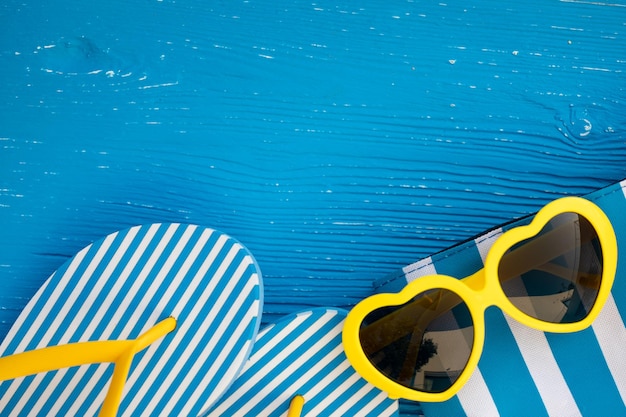 Chanclas de playa y gafas de sol sobre fondo de madera azul Vacaciones de verano y concepto de viaje