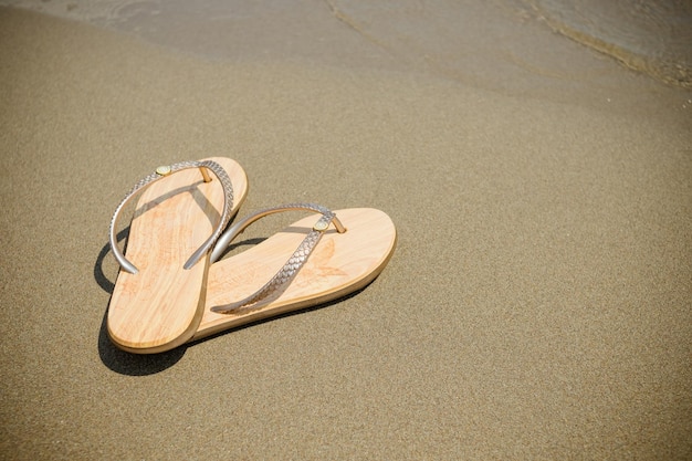 Chanclas de playa rosa sobre una arena clara Textura de arena clara El concepto de unas vacaciones en la playa Zapatos de verano Bofetadas de moda Sandalias Concepto de vacaciones de verano Espacio de copia