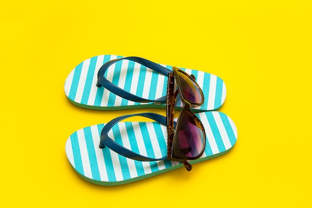 Chanclas a rayas con gafas de sol sobre un fondo amarillo vacaciones de verano