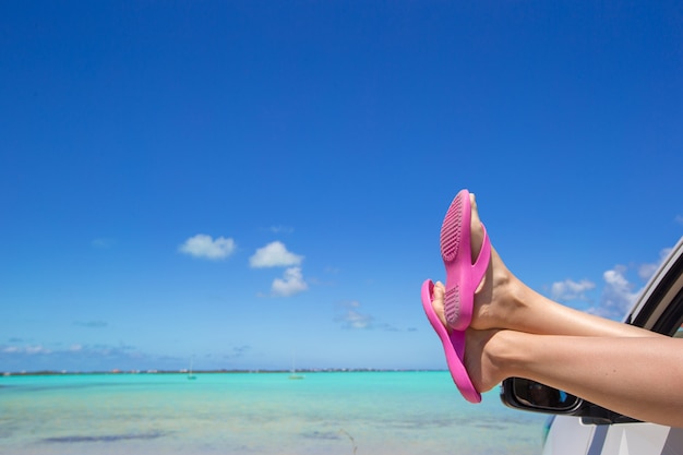 Chanclas desde la ventana de un automóvil en una playa tropical