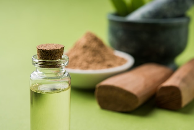 Chandan o polvo de sándalo con palos, mortero tradicional, perfume o aceite en frasco en miniatura y hojas verdes. enfoque selectivo