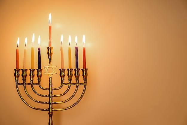 Chanukka-menorah mit brennenden Farbkerzen für jüdischen Feiertag mit hölzernem Hintergrund.