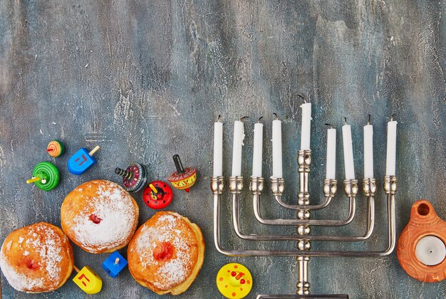 Foto chanukka-tabelle, die einen kerzenständer mit kerzen, donut und kreiseln auf blau einstellt