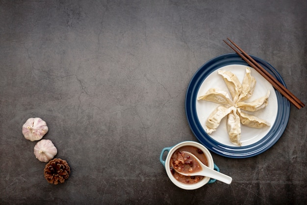 Foto chapa branca com dim sum e alho em um fundo cinza