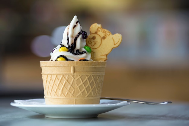 Chapa branca com sobremesa de sorvete no copo de bolacha com biscoitos de chocolate e cobertura de decoração criativa no interior colorido turva