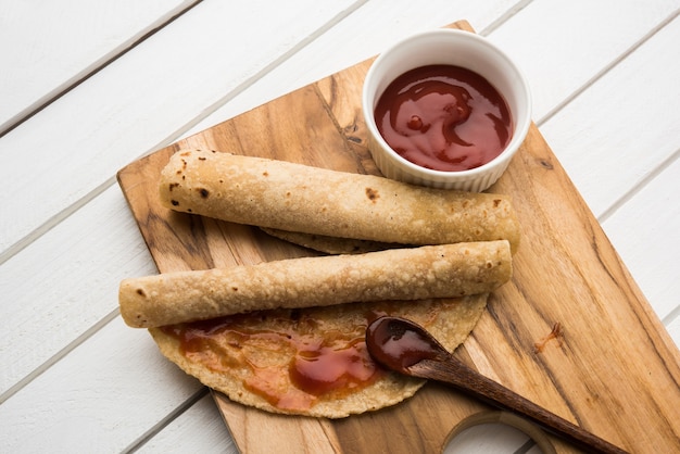 Chapati Roll mit Tomatenketchup oder Fruit Jam Jelly mit Smiley-Gesicht, indisches Kinder-Lieblingsmenü für Schultiffin-Box, selektiver Fokus