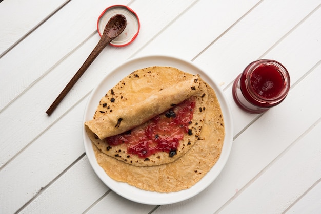 Chapati Roll mit Tomatenketchup oder Fruit Jam Jelly mit Smiley-Gesicht, indisches Kinder-Lieblingsmenü für Schultiffin-Box, selektiver Fokus