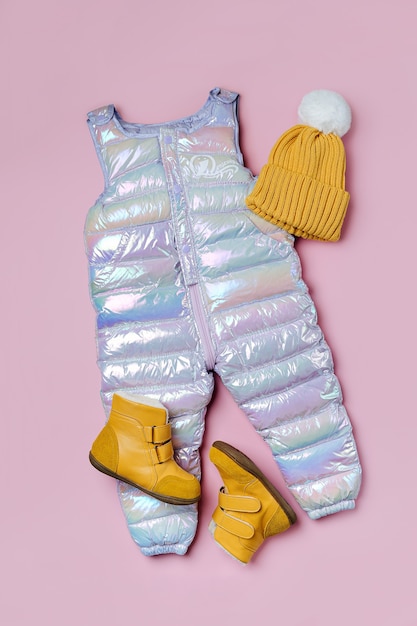 Foto chapéu de calças quentes e botas em fundo rosa. conjunto de roupas de bebê para o inverno. roupa de moda infantil.
