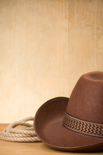 Foto chapéu de cowboy marrom e corda na madeira