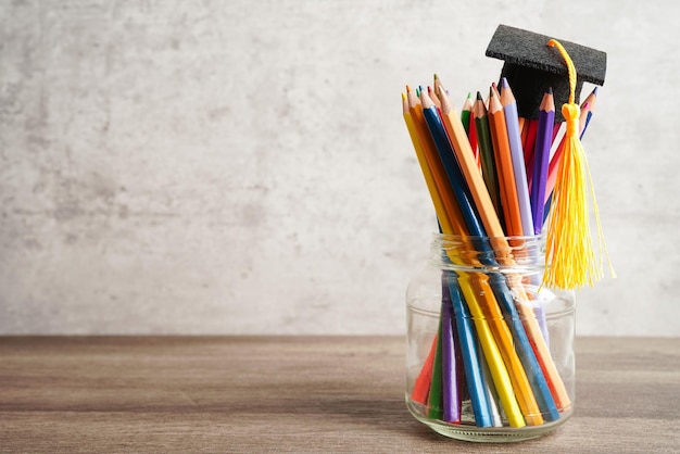 Chapéu de formatura com lápis coloridos no livro com espaço de cópia aprendendo o conceito de educação universitária