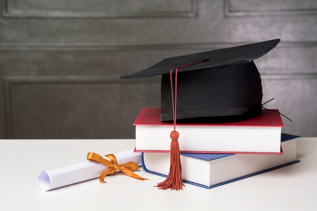 Chapéu de formatura com livros na mesa branca, fundo de educação
