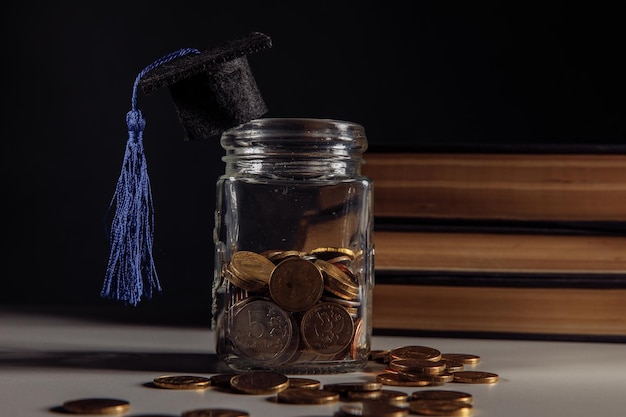 Chapéu de formatura na jarra com moedas em uma mesa. Conceito de dinheiro de bolsa de estudos