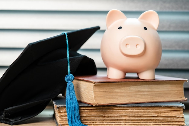 Chapéu de formatura preto e conceito de cofrinho investimento em educação graduação economiza dinheiro para educação