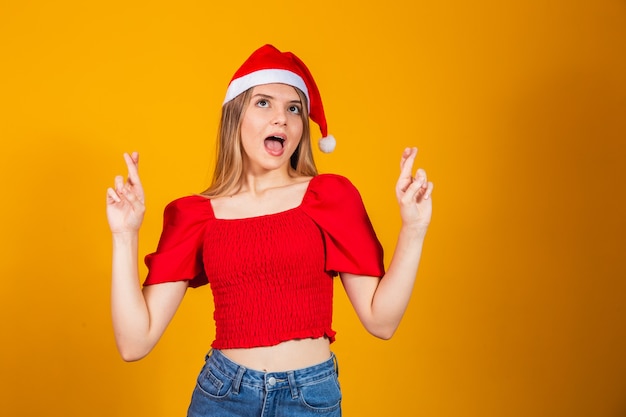Chapéu de mulher Papai Noel cruzou os dedos. Emoção positiva, expressão facial