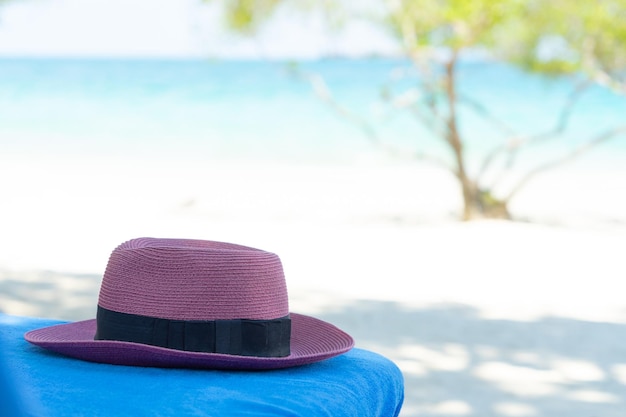 Chapéu de mulher roxo na cadeira de praia no fundo da praia com espaço de cópia