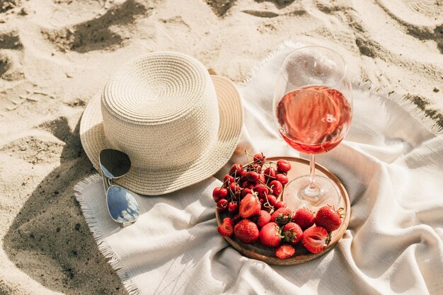Chapéu de palha com aba para proteção solar com prato de frutas e vinho