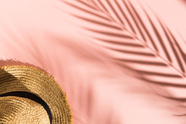chapéu de palha em fundo rosa com sombras