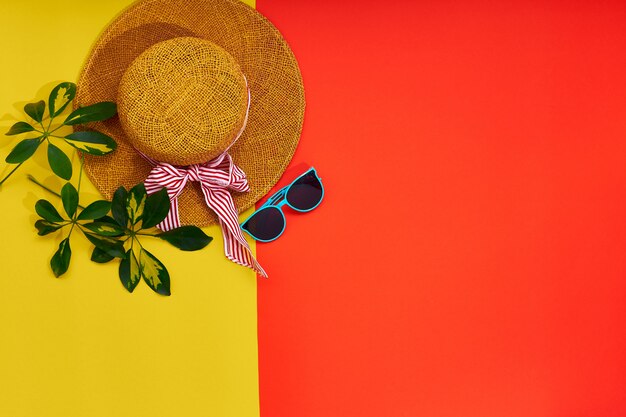 Chapéu de palha, óculos de sol, isolados em um fundo vermelho amarelo