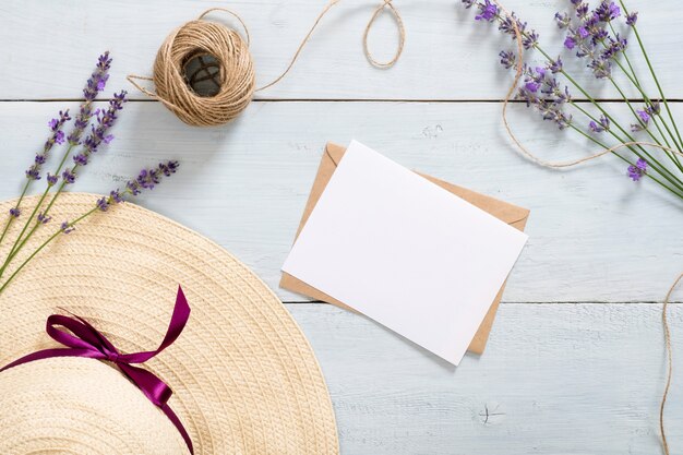 Chapéu de palha vintage, envelope de papel ofício, carta, barbante, flor de lavanda na mesa de madeira azul rústica