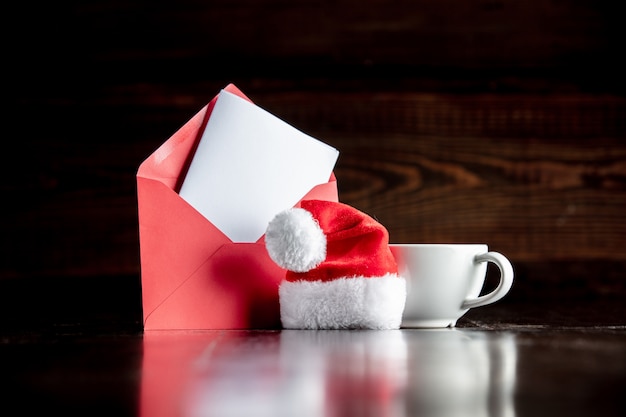 Foto chapéu de papai noel e copo com envelope