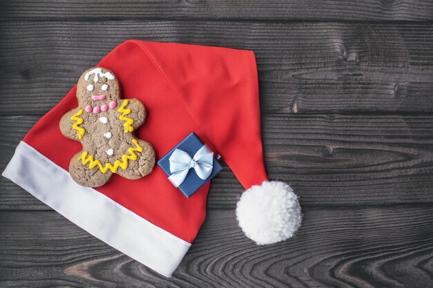 Chapéu de papai noel e pão de mel em forma de homem em madeira escura