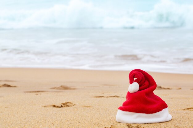 Chapéu de Papai Noel na areia do oceano