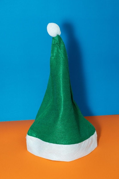 Chapéu de Papai Noel verde em fundo laranja e azul