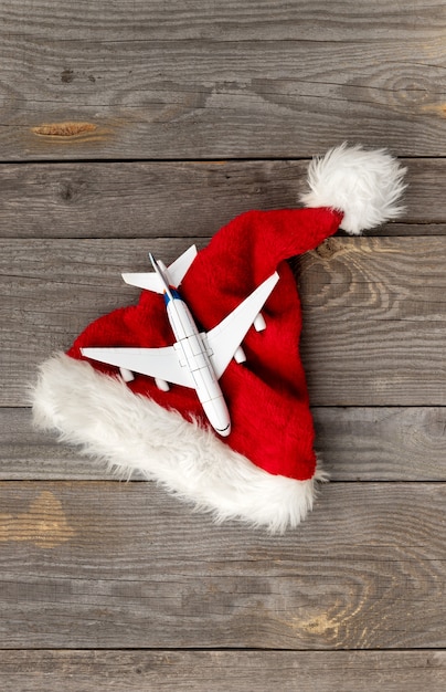 Chapéu de papai noel vermelho com avião de brinquedo na madeira velha.