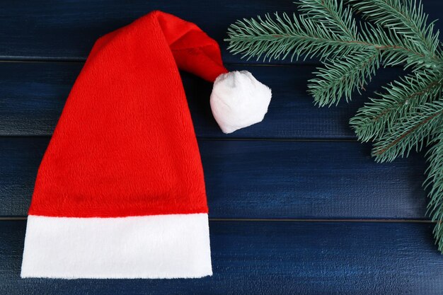 Chapéu de Papai Noel vermelho com galho de árvore do abeto na cor de fundo de madeira