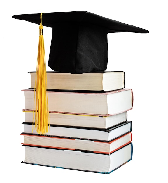 Chapéu de pós-graduação com borla amarela na pilha de livros isolados no fundo branco