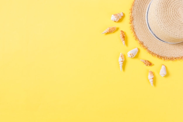 Chapéu de praia com conchas na mesa amarelo marrom. conceito de fundo de verão com vista superior do espaço da cópia.